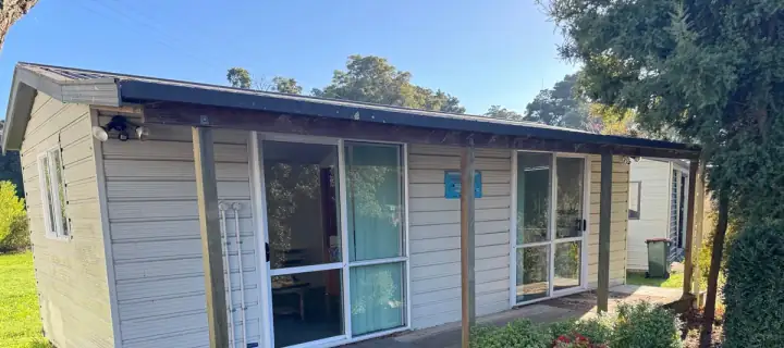 A single-storey cabin with cleaned cladding, roofline and path
